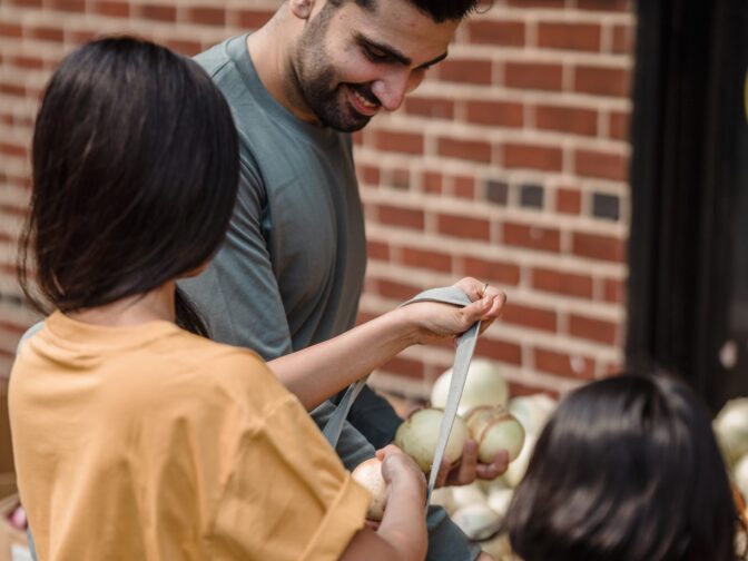 Man putting onions in bag with children